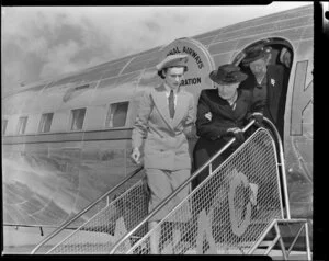 Helen Wood airport hostess escorting passengers off a New Zealand National Airways Corporation flight, Whenuapai