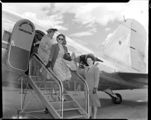 Miss Penner, Christchurch airport hostess, helping passengers off a National Airways Corporation aircraft