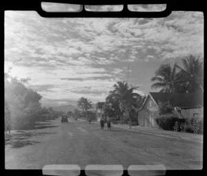 Two Fijians walking down a street in Lautoka, Fiji; a building with a sign Northern Hotels Wine & Spirit Merchants can be seen