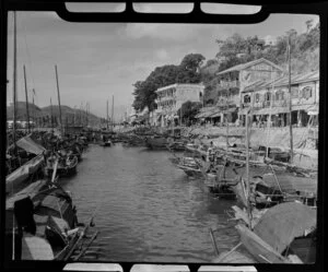 Harbour crowded with Chinese fishing boats or sampans, with cafes and other shops lining the street, Hong Kong