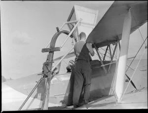 Ihumatao, Mangere, Manukau city, Auckland Region, featuring fertiliser being funnelled into an aerial topdressing plane [ZK-ANN Tiger Moth?] by an unidentified man