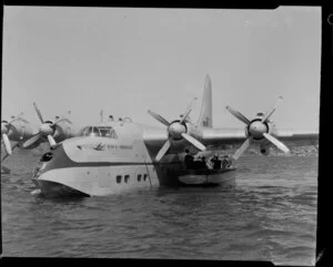 Unidentified passengers and Tasman Empire Airways Limited crew board the Short S.45 Solent flying boat, R.M.A Araragi (ZK-AMM), from a boat drawn up alongside it, Evans Bay, Wellington