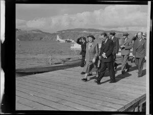 Unidentified passengers on the wharf at the the flying boat base near Hataitai Beach, Wellington, with the Tasman Empire Airways Limited Short S.45 Solent flying boat, R.M.A Araragi (ZK-AMM), moored in Evans Bay in the background
