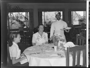 Unidentified woman and girl being served a meal in the dining room of the Northern Hotels, Fiji