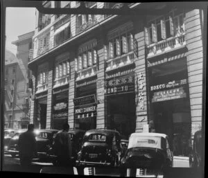 Busy scene in Pedder Street, Hong Kong, including businesses such as Graeco Egyptian Tobacco & Coffee Store, The Hong Kong Money Changer, N Lazarus Opticians, Bosco, and Auw Pi Seng's Trading Co Ltd