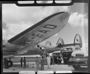 Qantas Empire Airways staff watch as passengers board the Lockheed L1049 Super Constellation (VH-EAD) aircraft Charles Kingsford Smith from a bus, Kallang Airport, Singapore