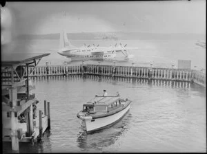 Motorboat moving toward the pier with the seaplane ZK-AMM behind