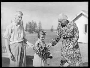 Unidentified man, woman and girl with bunch of bananas, Norfolk Island