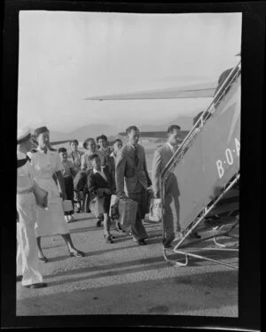 Qantas Empire Airways staff stand by as unidentified passengers board a Douglas DC-4 (VH-EBK) Skymaster aircraft at Kai-Tak Airport, Kowloon, Hong Kong