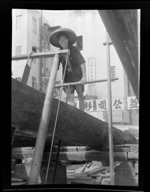 An unidentified Chinese man sawing a log of timber, Kowloon, Hong Kong