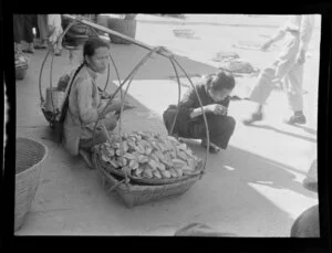 Market scene, Hong Kong, featuring an unidentified woman selling star fruit from baskets joined by a shoulder yoke