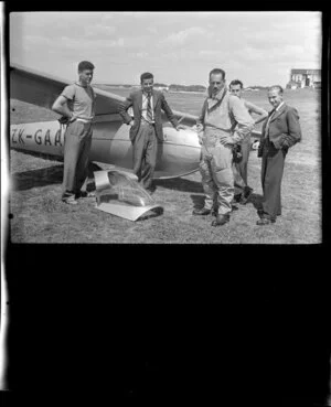 Mr G Hookings and a group of unidentified men standing next to his glider at Mangere, Auckland