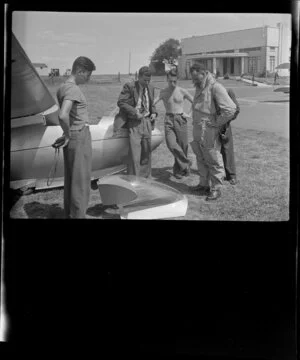 Mr G Hookings and a group of unidentified men standing next to his glider at Mangere, Auckland