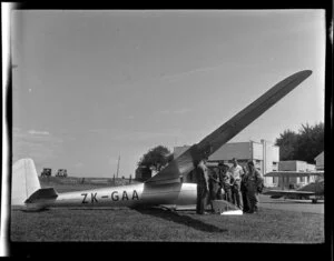 Mr G Hookings and a group of unidentified men standing next to his glider at Mangere, Auckland