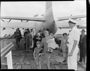 Unidentified Tasman Empire Airways Ltd Solent seaplane air hostess leaving the aircraft with two children, Mechanics Bay, Auckland