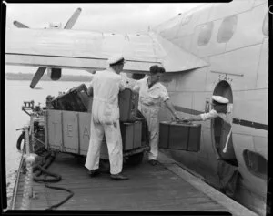 Luggage being unloaded by unidentified crew from the Tasman Empire Airways Ltd Solent seaplane Ararangi, Mechanics Bay, Auckland