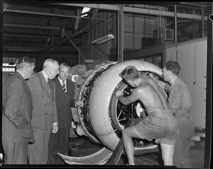 From left, Tasman Empire Airways Chairman Sir Leonard Isitt, British Overseas Airways Corporation Chairman Sir Miles Thomas, and an unidentified airline employee, looking at an aircraft engine being serviced by mechanics