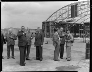 British Overseas Airways Corporation and Tasman Empire Airways Limited employees, including (from third left) Mr Barrow, Sir Miles Thomas (chairman BOAC), and (on far right) photographer Leo Lemuel White, on the tarmac at an unidentified airport with a hangar being constructed in the background