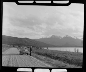 Unidentified man and Morris Minor beside Lake Manapouri, Southland district