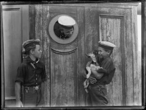 Three unidentified sea cadets with a dog [puppy] on board four-masted barque Rewa, location unknown