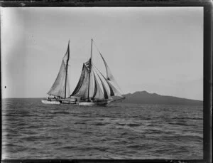 Sailing ship Ngaru carrying timber, Waitemata Harbour, Auckland Region, with Rangitoto Island in the background