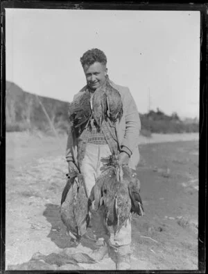Duck shooting, featuring unidentified hunter with gun and duck carcasses, location unknown