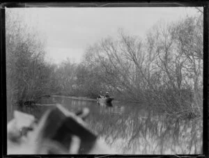 Duck shooting, featuring unidentified hunters in boat on waterway, location unknown