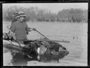 Duck shooting, featuring unidentified hunters in boat laden with dead ducks, location unknown