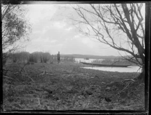 Duck shooting, featuring an unidentified hunter walking to a boat on the edge of the water, location unknown