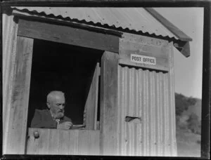 Postmaster Walter Strawbridge sorting mail in a corrugated shed, Oaro Post Office, Kaikoura coast