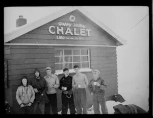 Unidentified group with hot drinks outside Happy Valley Chalet while skiing on Coronet Peak, Otago