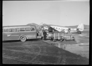Luggage being unloaded from a Dunedin Taxis Ltd bus for the aircraft ZK-AOP, National Airways Corporation, [Taieri?] airport