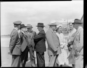 Prime Minister Sidney Holland at Whenuapai Airport, Auckland, talking with unidentified group of men