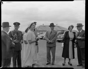 Prime Minister Sidney Holland and family with unidentified group of men at Whenuapai Airport, Auckland