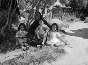 Portrait of woman with three children, sitting under a tree