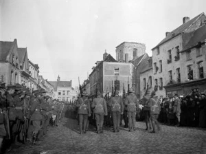 New Zealand troops marching through the bombed town of Le Quesnoy, France
