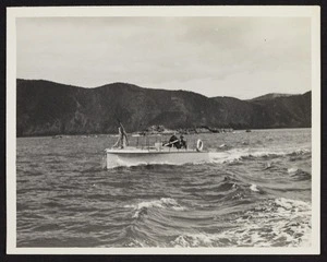 1930's steel whaling boat in ocean with two men sitting on deck