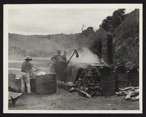 Three men boiling blubber in cauldron with processing barrels in the foreground
