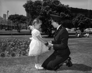 Kneeling policewoman talking to a young girl in a park