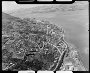 View of Ravensbourne looking North, showing residential housing, Ravenbourne Road (State Highway 88) and part of Ravensdown Fertiliser Works with Moller Park and wharf, with Macandrew Bay and farmland across inner Dunedin Harbour