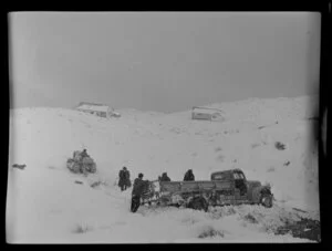 Caterpillar tractor driver about to tow out a truck stuck in a snowdrift during a snowfall, Coronet Peak, Otago