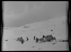 Men and caterpillar tractor attempting to tow out a truck stuck in snow during a snowfall, Coronet Peak, Otago