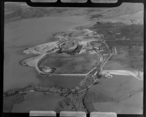 Close-up view of Huntly open cast coal mine beside lake, Waikato District, showing open pit with heavy machinery, buildings with farmland beyond