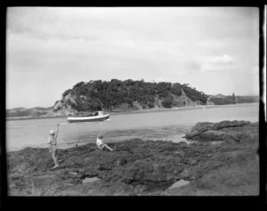 Children on rocks waving at passenger boat Miss Knoxie, Paihia, Bay of Islands