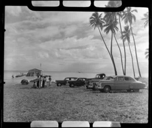 Satupuala Base, Upolu, Samoa, showing men, cars and TEAL (Tasman Empire Airways Limited) ZK-AMM flying boat at Samoa