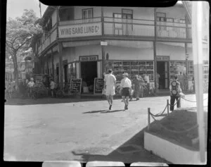 Road scene at Papeete, Tahiti, shows local store Wing Sang Lung Cie and locals shopping