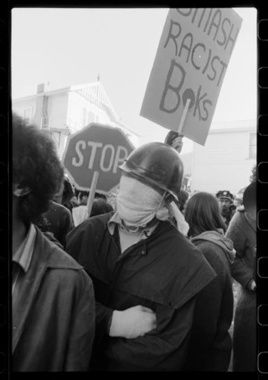 Masked protester with "Smash Racist Boks" sign