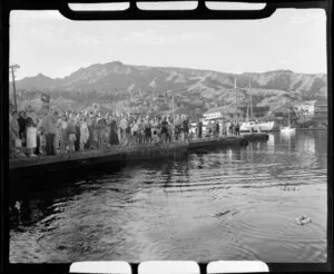 Locals watch from waterfront as TEAL (Tasman Empire Airways Limited) flying boat departs Tahiti, shows buildings, boats and hills