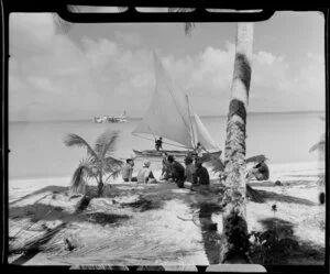 Locals on beach, Akaiami, Aitutaki, Cook Islands, including sail boat and TEAL (Tasman Empire Airways Limited) Flying boat in the distance