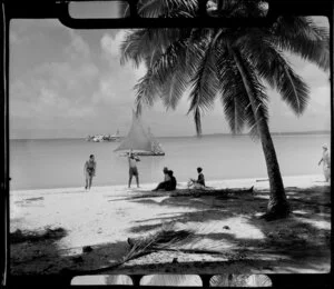 Locals on beach, Akaiami, Aitutaki, Cook Islands, showing canoe and TEAL (Tasmam Empire Airways Limited) Flying boat in the lagoon